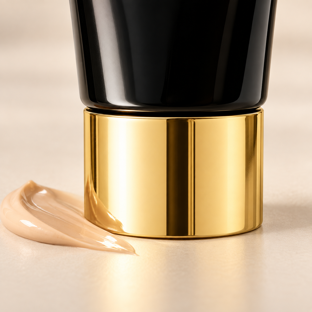 Detail of body makeup tube gold-tone cap beside a warm beige cream swatch