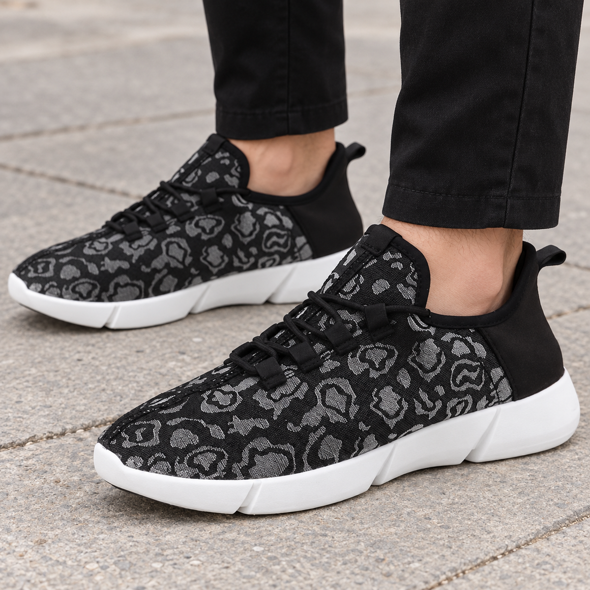 Black patterned sneakers worn with lights off