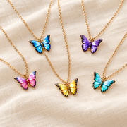 Five colorful butterfly pendant necklaces on cream fabric